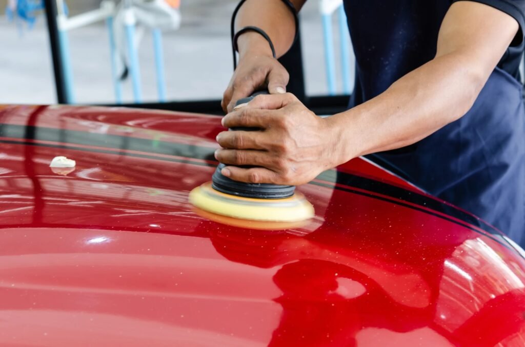 Professional car waxing being performed with a polishing machine on a red vehicle in Frisco TX