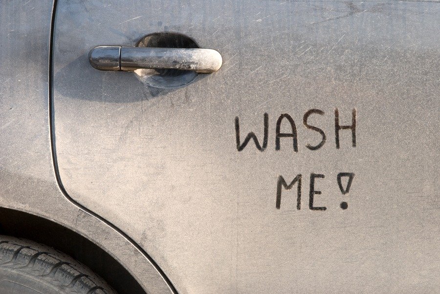 Dirty car door with “Wash Me!” written in the dust

