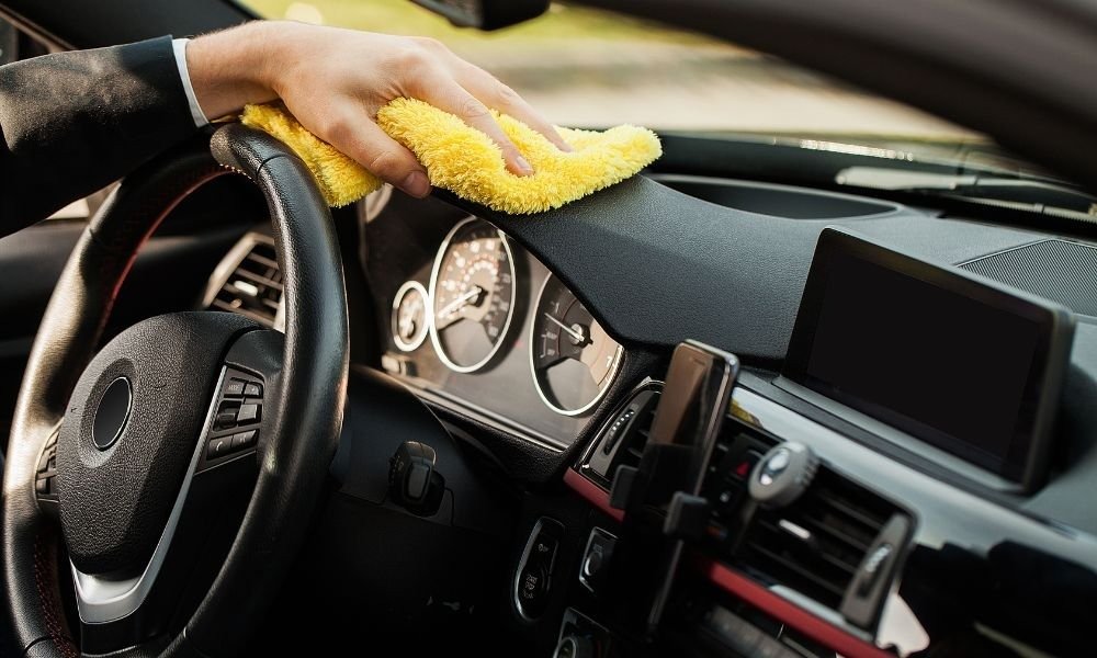 Interior car detailing with a microfiber cloth on the dashboard and the steering wheel