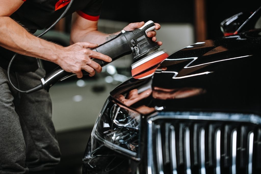 Machine polishing black luxury car hood in Frisco TX detail shop