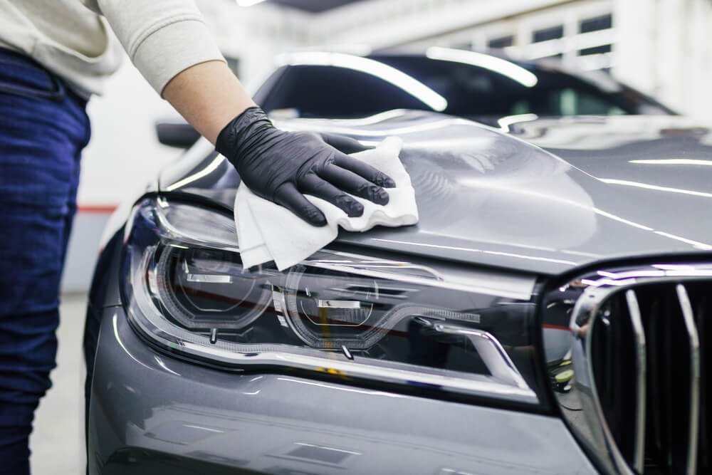 Technician performing exterior car detailing on luxury vehicle
