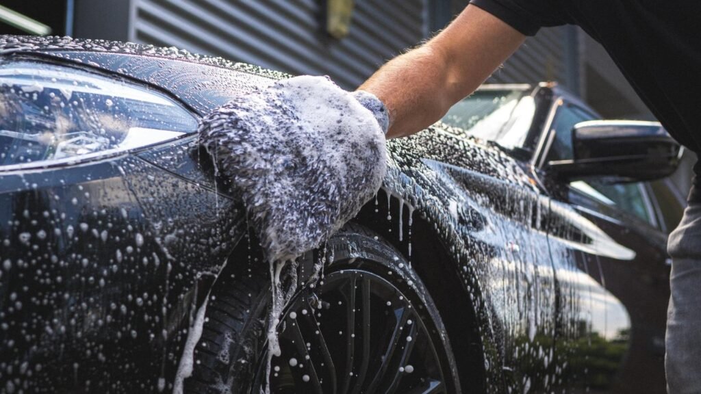 A man hand car washing a black car with soft cloth